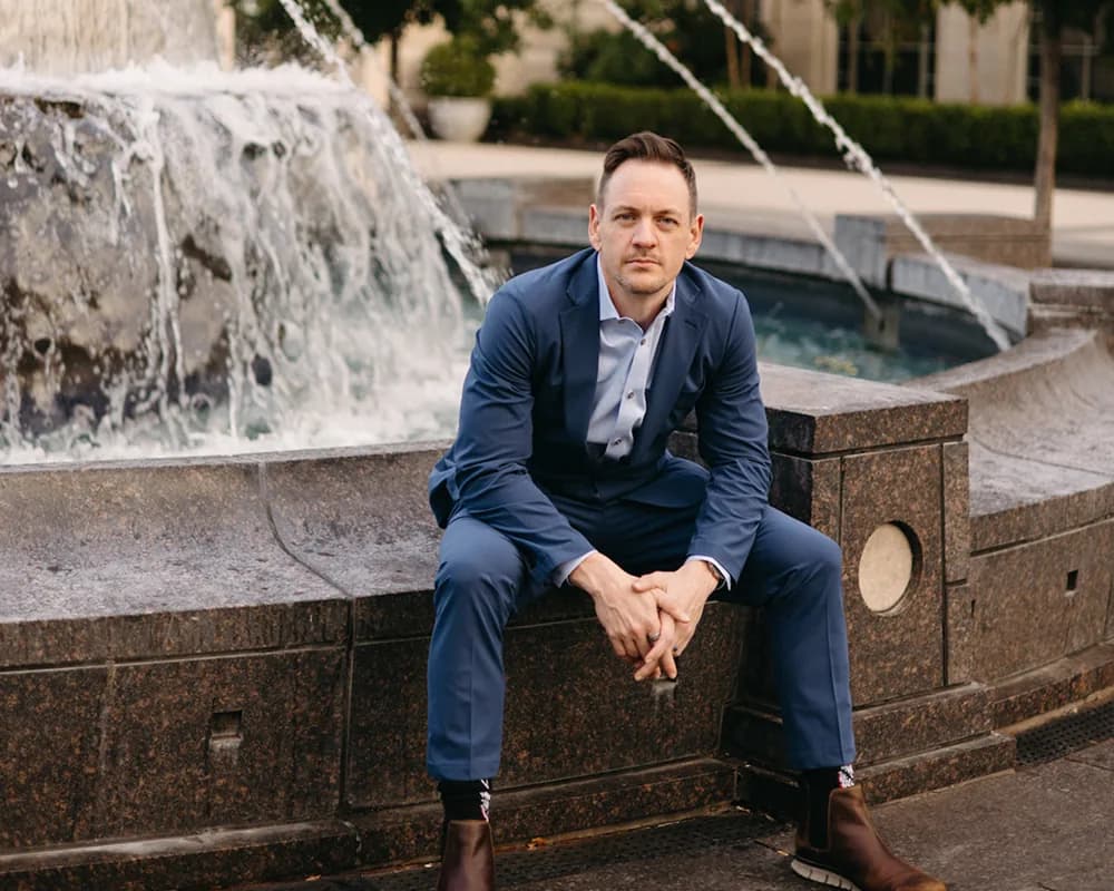 Arron Bennett seated beside a city fountain